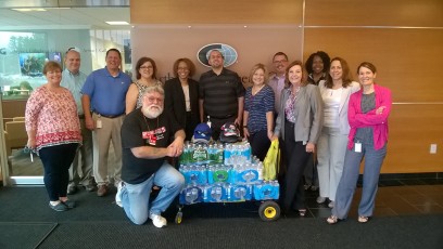 Thank-you to the energetic team of AJ Gallagher & Co that recently donated water, t-shirts, hats, sunglasses & sunscreen for the 2017 OCO Summer Homeless Outreach Water Drive.The AJG Team from left to right are: Eileen O., Ted G., Joe C., Susan B., Tawana W., Rob C., Sandy H., Elias R., Veronica C., Marya M., Linda F., and Cheryl C. Kneeling is OCO Volunteer Stephen S.