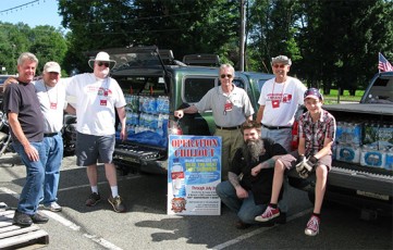 OCO Team loads 97 cases of life saving water for delivery to homeless veterans throughout NJ, collected by Tramontin Harley Davidson, Hope, NJ, from generous riders during their annual Wet the Vet water drive. L to R : Joe Brzezowski, MAJ Tony DeStefano, John Hennessey, Dcn. Ray Chimileski, Ken Steffans, kneeling with beard Paul, on tail gate Joshua Steffans.